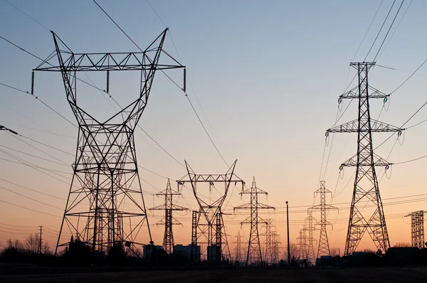 Ηλεκτρικές πύργους μετάδοσης (πυλώνων ηλεκτρικής ενέργειας) στο ηλιοβασίλεμα Εικόνα Αρχείου