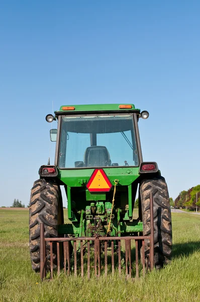 Zelený traktor v oblasti hospodářství s modrou oblohou — Stock fotografie