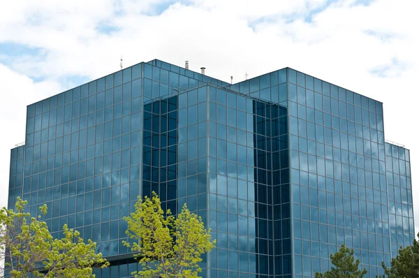 Immeuble de bureaux moderne avec arbres et nuages — Photo