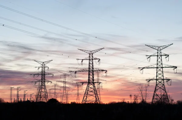 Elektromos átviteli tornyok (villamosenergia-oszlop), a naplemente — Stock Fotó
