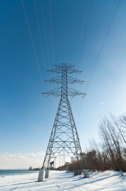 yüksek gerilim hatları göl kışın taşıyan bir elektrik iletim kulesi.