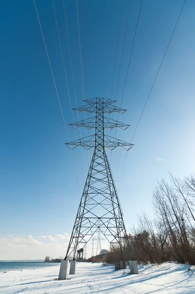stock image An electrical transmission tower carrying high voltage lines beside a lake in winter.