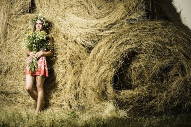 Beautiful woman with flowers near a haystack clipart