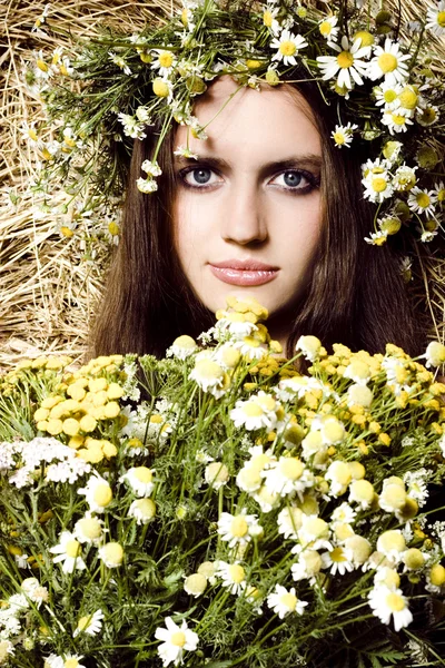 Mulher bonita com flores perto de um palheiro — Fotografia de Stock