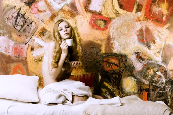 Портрет молодої блондинки в ліжку на тлі мистецтва — стокове фото