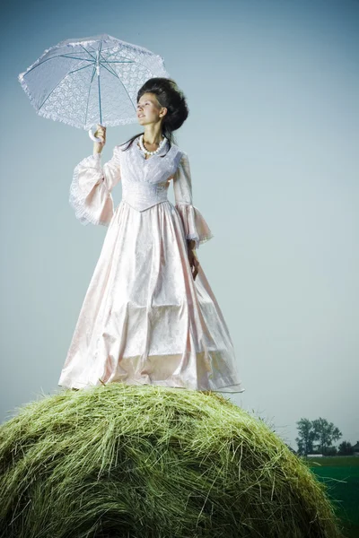 Красивая женщина в винтажном платье стоит на стоге сена — стоковое фото