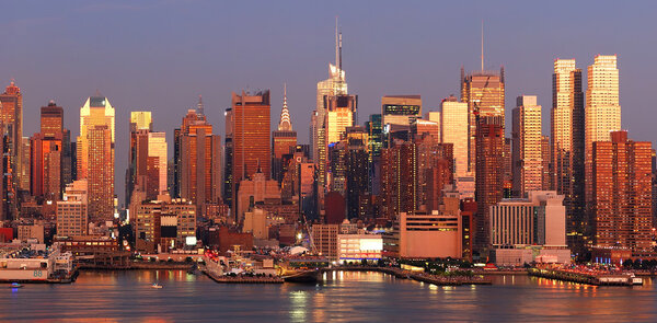 New York City Manhattan skyline panorama at sunset with Times Square and skyscrapers with reflection over Hudson river.