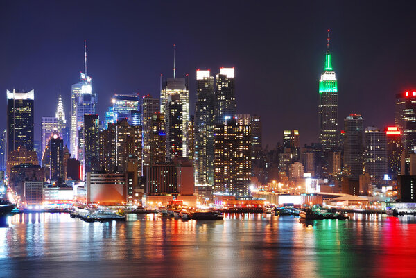Empire State Building in New York City with Manhattan Skyline at night panorama over Hudson River with reflection.