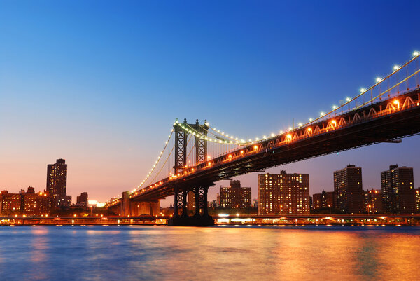 New York City Manhattan Bridge over Hudson River with skyline after sunset night view illuminated with lights viewed from Brooklyn.