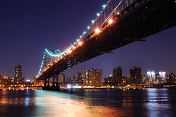 New York City Manhattan Bridge over Hudson River with skyline after sunset night view illuminated with lights viewed from Brooklyn.