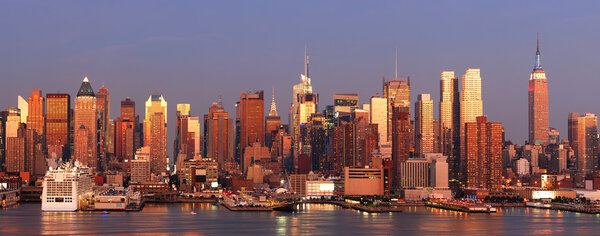 New York City Manhattan skyline panorama at sunset with empire state building, Times Square and skyscrapers with reflection over Hudson river.