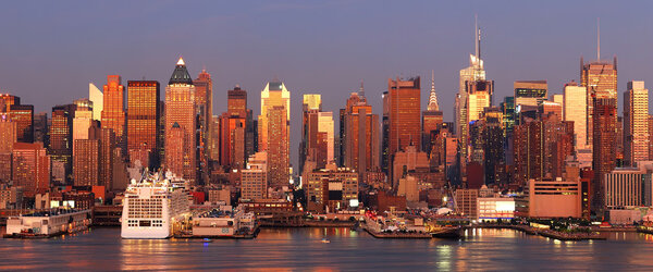 Urban city sunset. New York City Manhattan skyline panorama at sunset with Times Square and skyscrapers with reflection over Hudson river.