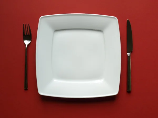 Arrangemet of a white dinner plate with fork and knife — Stock Photo, Image