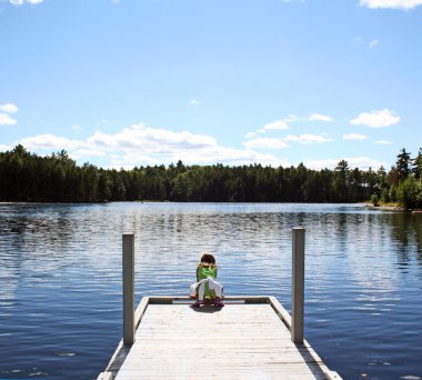 Child on dock at lake clipart
