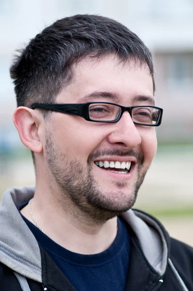 Ritratto di un giovane uomo barbuto sorridente con gli occhiali Foto Stock Royalty Free
