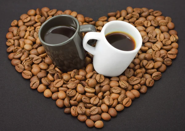 Dos gorras y granos de café como un corazón —  Fotos de Stock