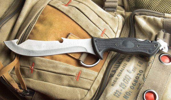 Army knife on a marching backpack background