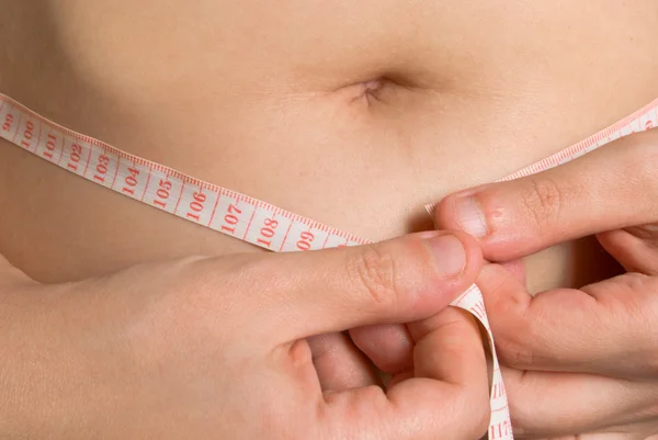 stock image The woman is measuring the stomach by a centimetric tape