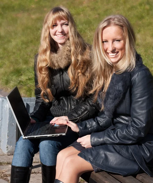 Gülümseyen bir dizüstü bilgisayar ile iki kız — Stok fotoğraf