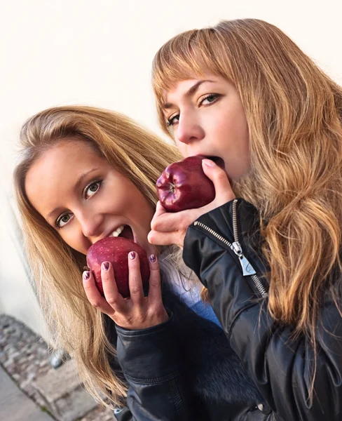 Due ragazze che mangiano mele rosse — Foto Stock