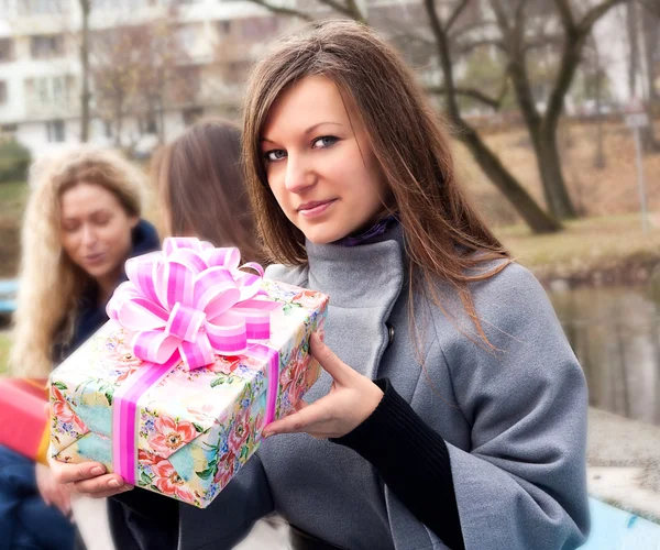 Beautiful young brunette girl holding a present — Stock Photo, Image