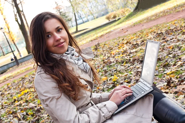 Hermosa chica joven con un ordenador portátil en el parque — Foto de Stock