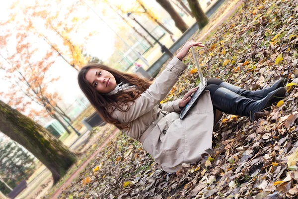 Beautiful young girl with a laptop in the park — Stockfoto