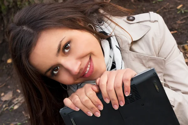 Mujer joven sonriente sosteniendo una computadora portátil — Foto de Stock