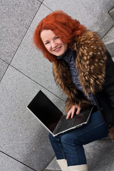 Menina sorrindo jovem com um laptop — Fotografia de Stock