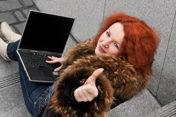 Ganska ung tjej med rött hår håller en laptop — Stockfoto
