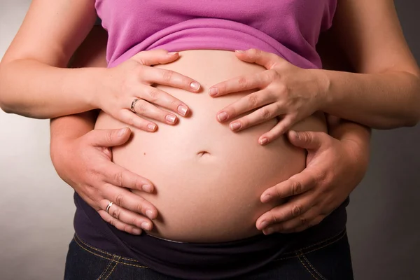 妊娠中の女性と彼女の夫の写真がスタジオにあります。胃の手を抱擁 — ストック写真