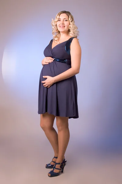 濃い青のドレスに妊娠中の母親の写真 — ストック写真