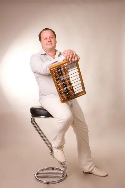 Stock image Man sits on a high chair with abacus in hands