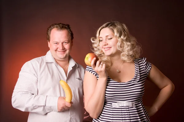 Foto del hombre y su esposa embarazada en un estudio con fruta — Foto de Stock