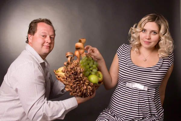 Foto de pareja matrimonial joven en un estudio con la cesta de fruta — Foto de Stock