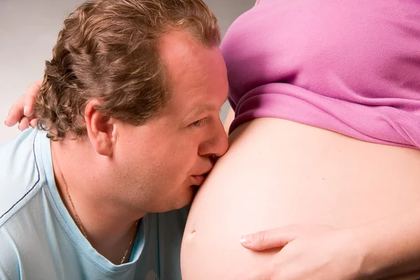 Mies suutelee raskaana olevaa vaimoa vatsaan — kuvapankkivalokuva