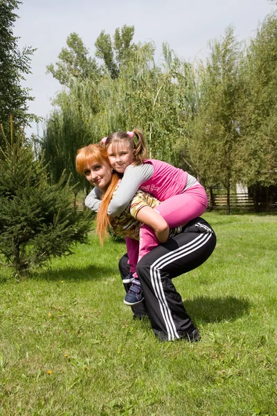 Mother and daughter do charging on a lawn — Stock Photo, Image