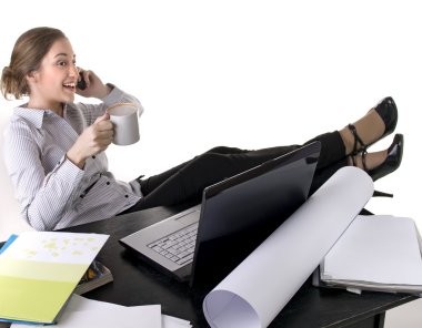 A beautiful young woman working on her laptop computer.Talks by mobile phone and drinks tea clipart