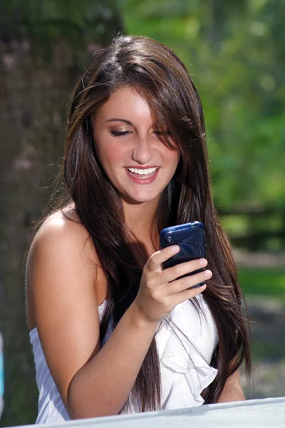 Piękne nastolatki brunetka SMS-ów na zewnątrz — Zdjęcie stockowe