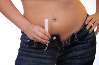 A young woman with camouflage fingernail tips holds a tampon. Selective focus on the tampon. clipart