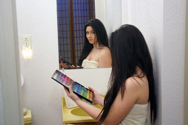 彼女のメイク パレットと好奇心や優柔不断な表情を持つ彼女の鏡の前で座っている 代の少女 — ストック写真