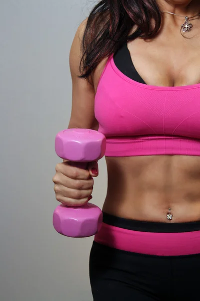 顕著な腹部の筋肉を持つ女性の運動選手の腹部 腰のクローズ アップ彼女はピンクの手の重量を保持しています — ストック写真