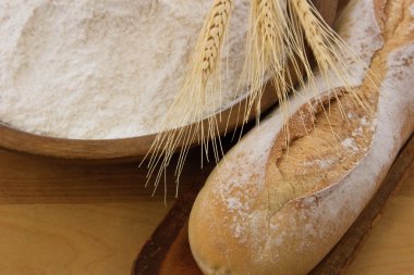 Crusty baguette bread with wooden bowl full of flour clipart