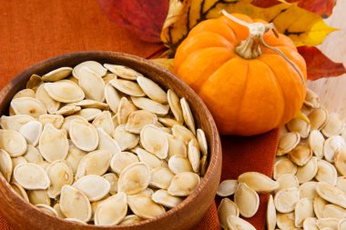 Close up of healthy pumpkin seeds and pumpkin against colorful autumn accen clipart