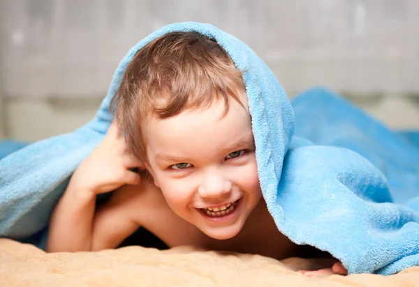 Kleine jongen onder een blauwe deken — Stockfoto