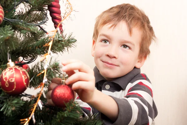 Boy decorates Christmas tree — Stock Photo, Image