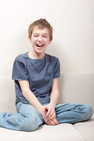 Підліток сидить на дивані і сміється — стокове фото