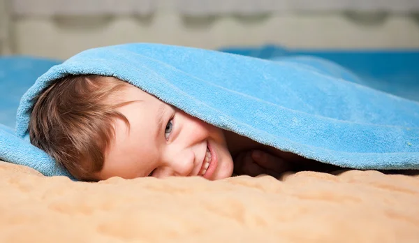Kleiner Junge unter einer blauen Decke — Stockfoto