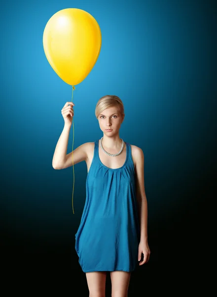 Blondynka w niebieska sukienka z żółtym balon — Zdjęcie stockowe