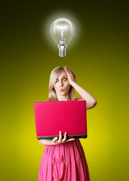 Blondine im rosa Kleid mit Laptop und Glühbirne — Stockfoto